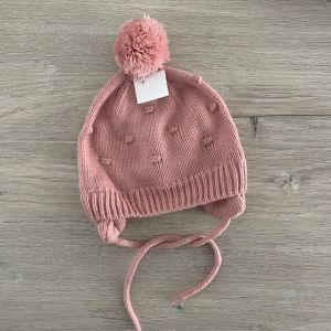 Roze gevoerde muts met pompon en oorflappen